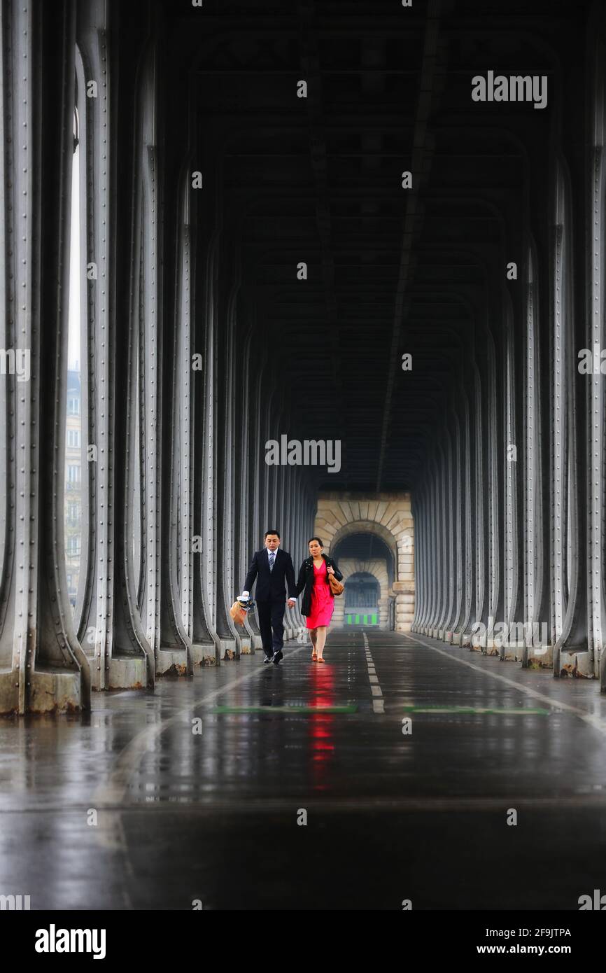 Paris, Frankreich verliebtes Pärchen spaziert bei Regenwetter unter der Brücke Bir Hakeim und spiegelt sich im nassen Asphalt der Straßen von Paris Stock Photo