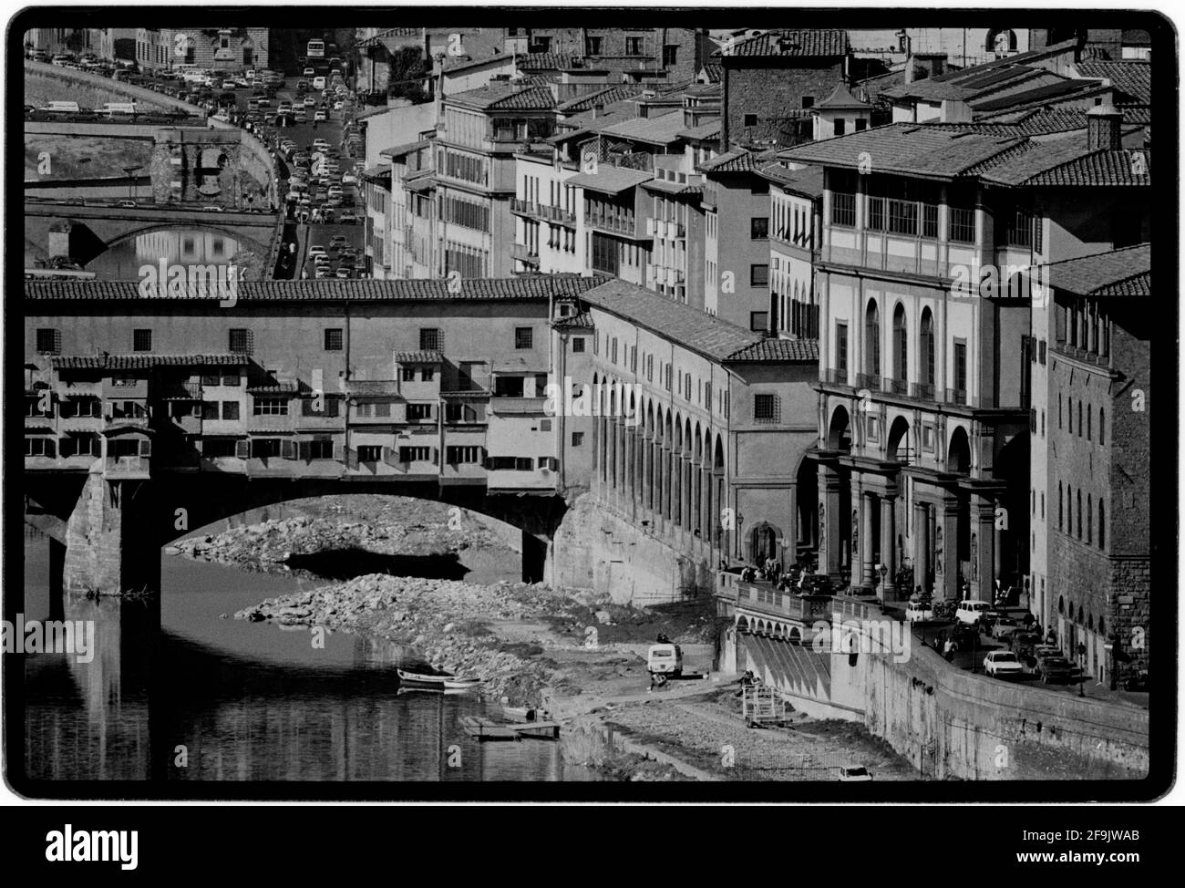 Florence Tuscany Italy 1982 Ponte Vecchio. The Ponte Vecchio 'Old Bridge',  is a medieval stone closed-spandrel segmental arch bridge over the Arno River, in Florence, Italy. It is noted for the shops built along it, as was once common. Butchers, tanners, and farmers initially occupied the shops; the present tenants are jewelers, art dealers, and souvenir sellers. Stock Photo