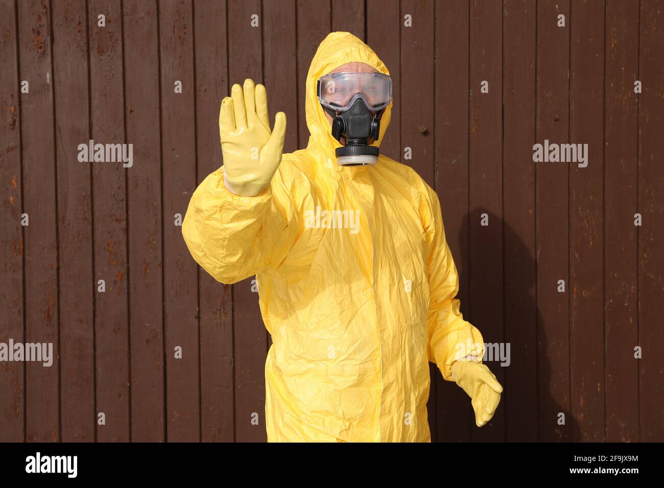 Mann im Schutzanzug hält die Hand hoch - workwear and protective clothing Stock Photo