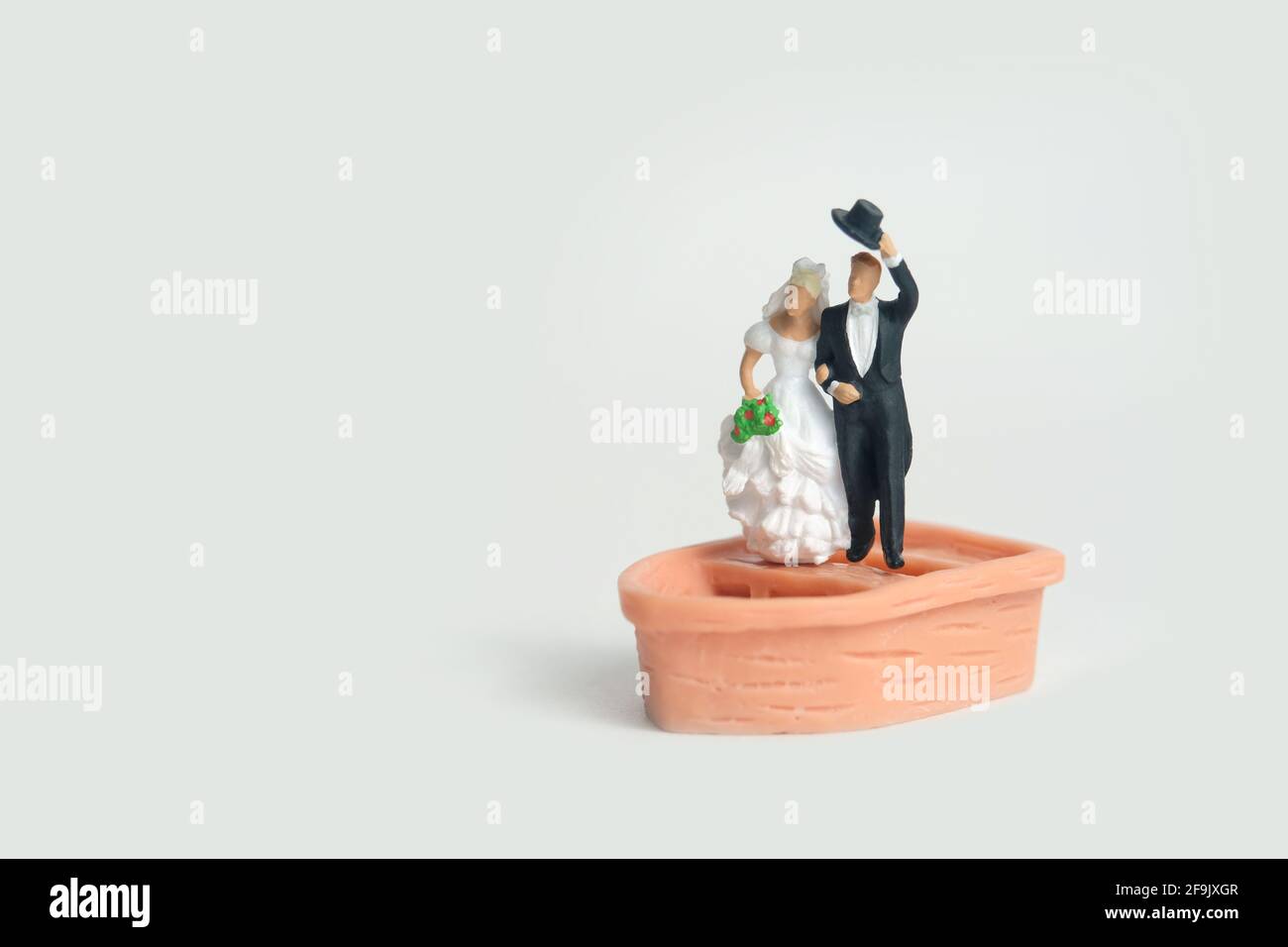 Bride and groom married miniature people stand above boat after wedding, isolated cut out on a white background. Image photo Stock Photo