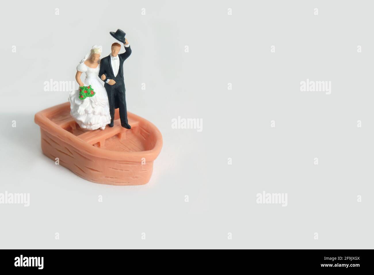 Bride and groom married miniature people stand above boat after wedding, isolated cut out on a white background. Image photo Stock Photo