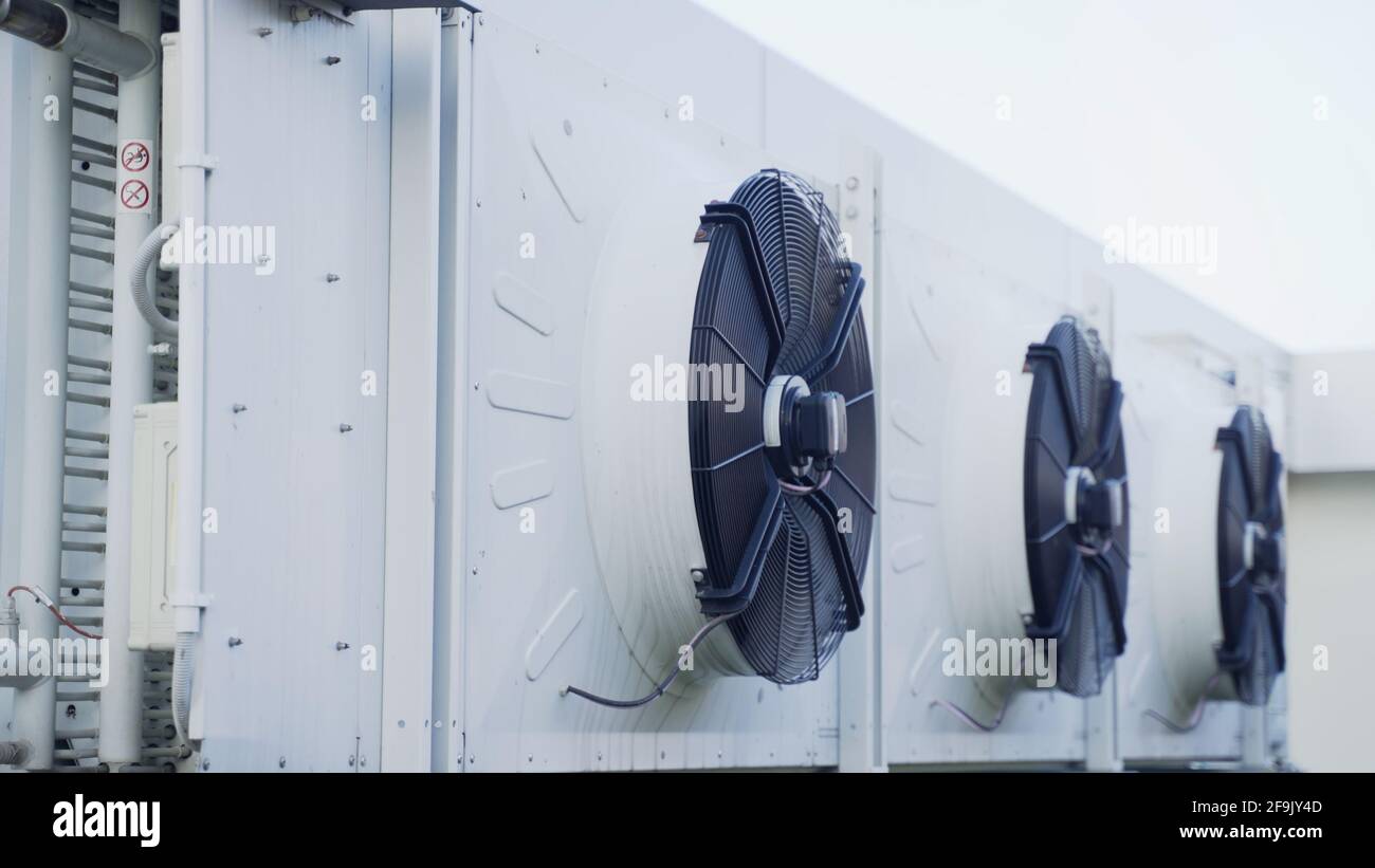 Close-up of row of three exterior air condition units. Grill covered electric fans. Detail of industrial building equipment. Stock Photo