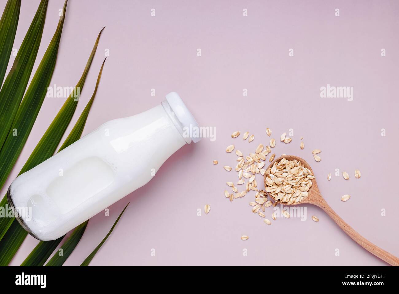 Bottle with daity free oat milk and dry oats in the spoon. Stock Photo