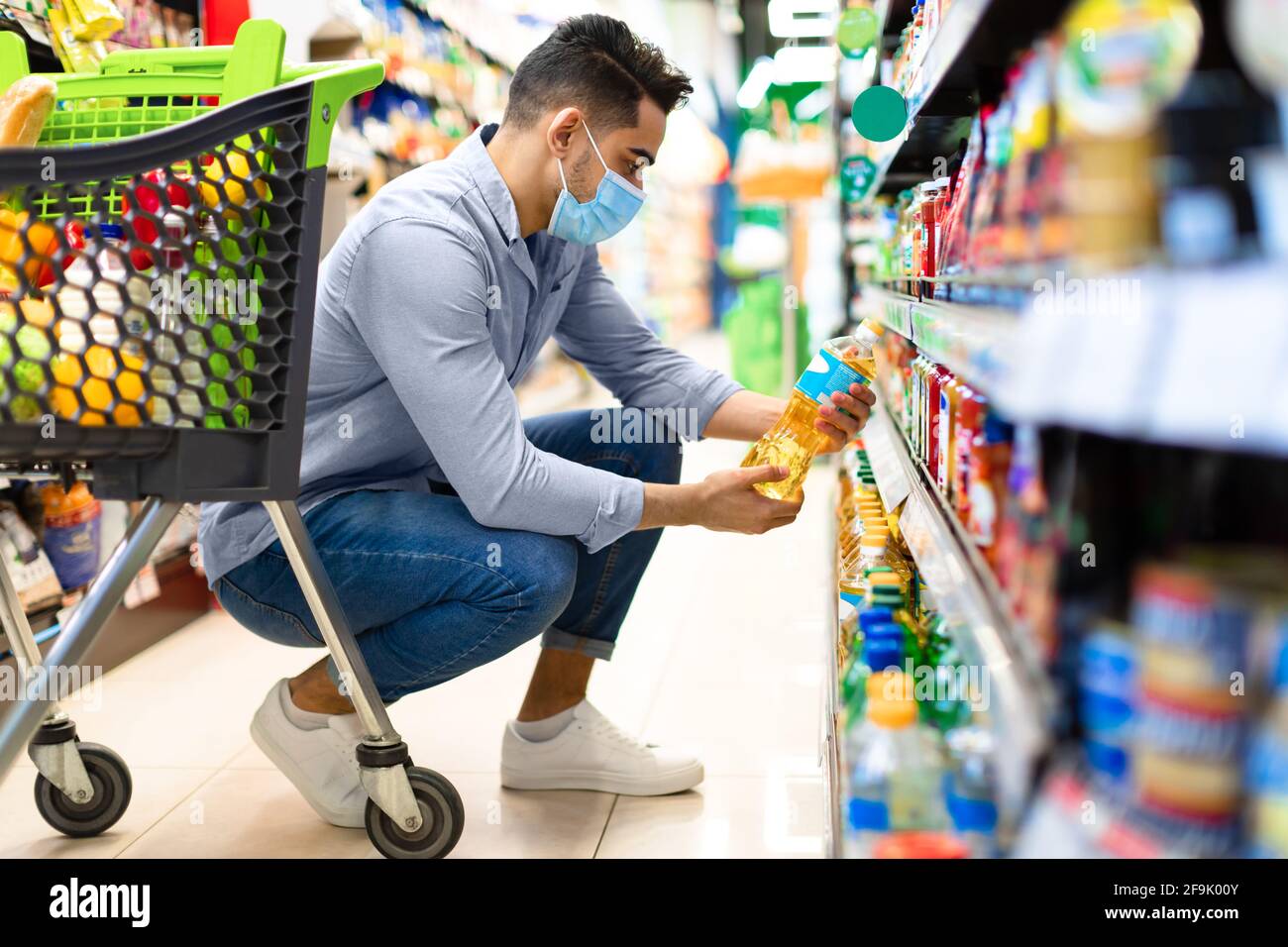 Middle-Eastern Man Doing Grocery Shopping Choosing Cooking Oil In Supermarket Stock Photo