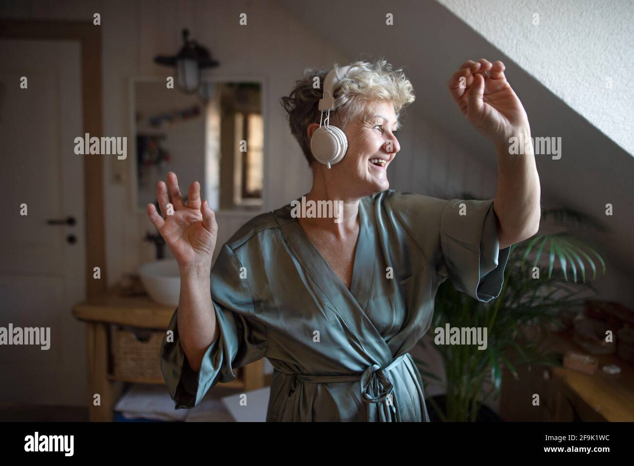 Happy senior woman with headphones dancing at home, relax and self-care concept. Stock Photo
