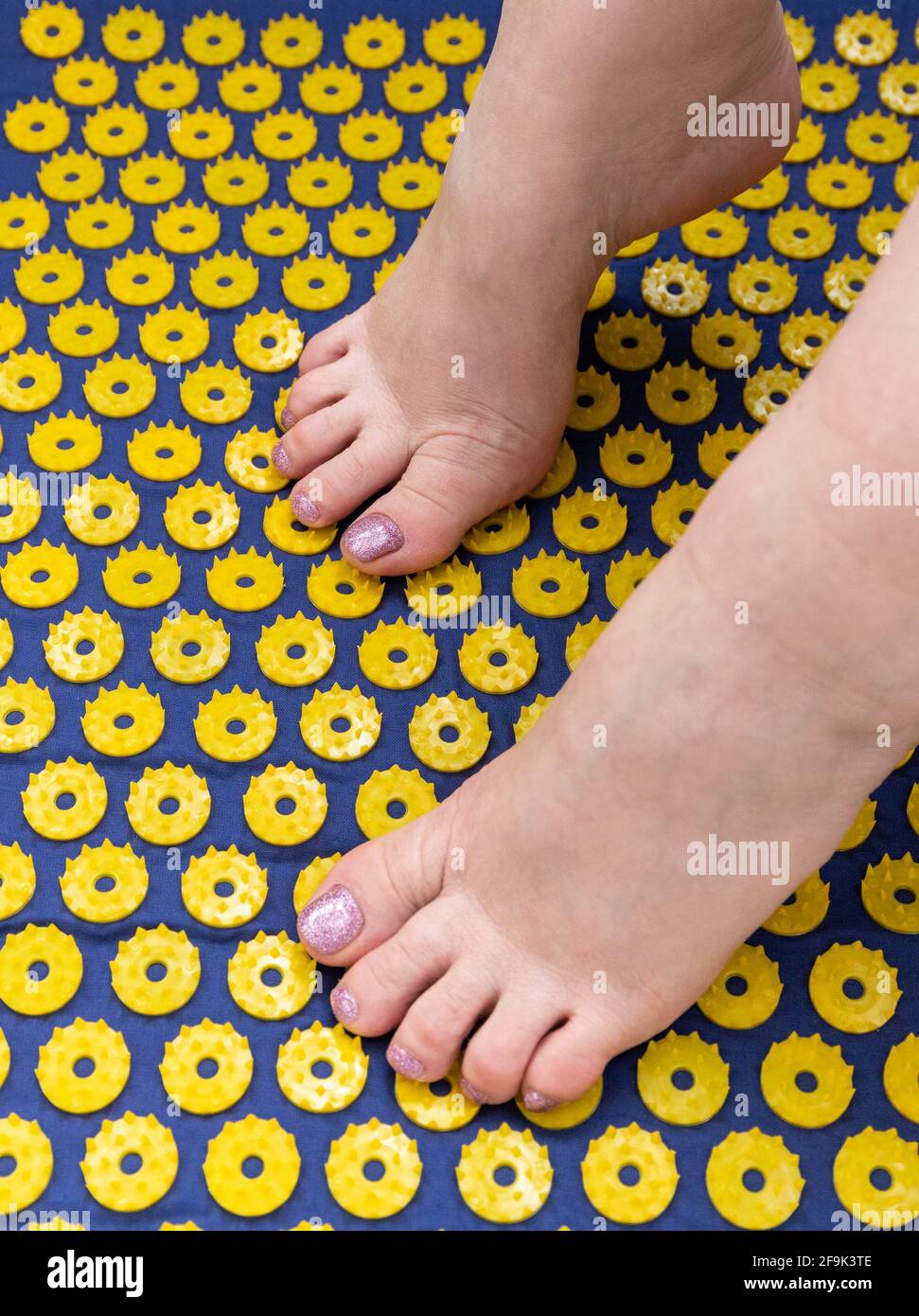 Women's feet stand on a needle mat foot massage using an applicator