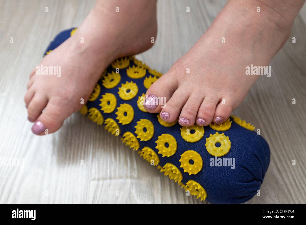Women's feet stand on a needle roller - foot massage using an applicator Kuznetsov, Russia Stock Photo