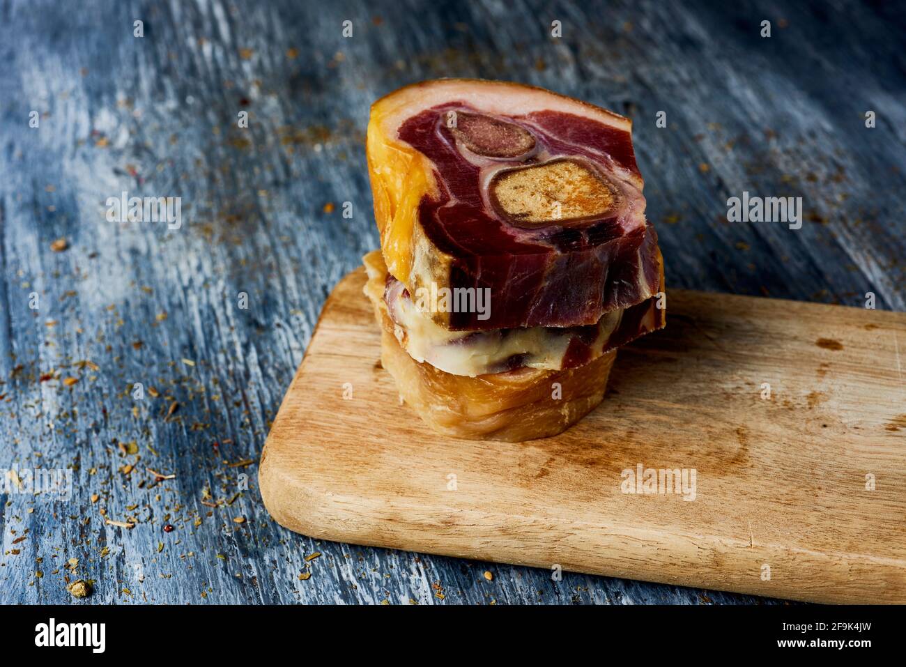 some cuts of codillo de jamon, spanish ham hock, on a chopping board placed on a gray rustic wooden table Stock Photo