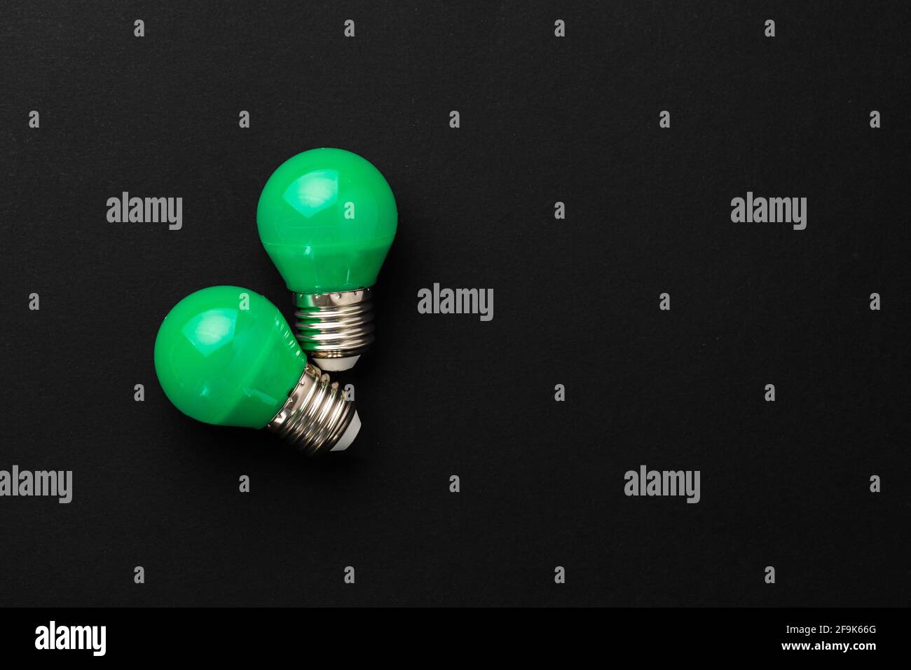 Two green light bulbs on black background Stock Photo