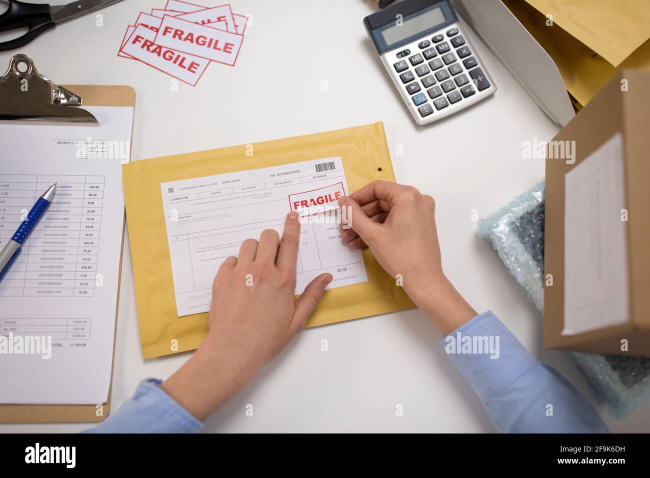 hands sticking fragile marks to parcel in envelope Stock Photo