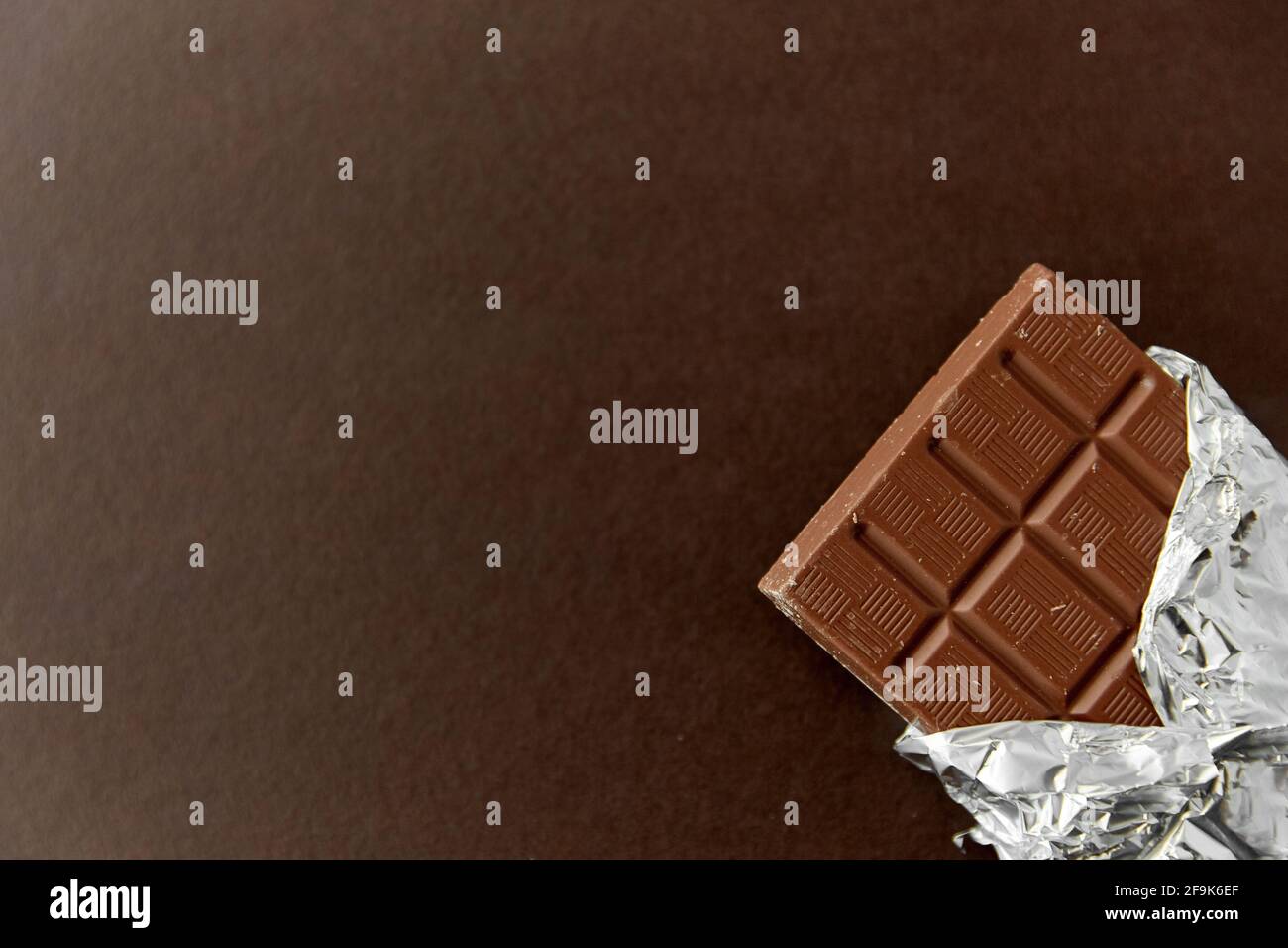 chocolate bar in foil wrapper on brown background Stock Photo Alamy