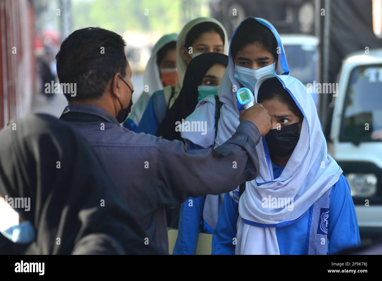 Lahore, Pakistan. 19th Apr, 2021. A security guard is checking the body temperature and sanitizing the shoes of girls students before entering in the educational Institutes. Government Kinaird girls high school from grade 9th to 12th is reopen after long vacation due to the third phase of Covid-19 in Lahore. (Photo by Rana Sajid Hussain/Pacific Press) Credit: Pacific Press Media Production Corp./Alamy Live News Stock Photo