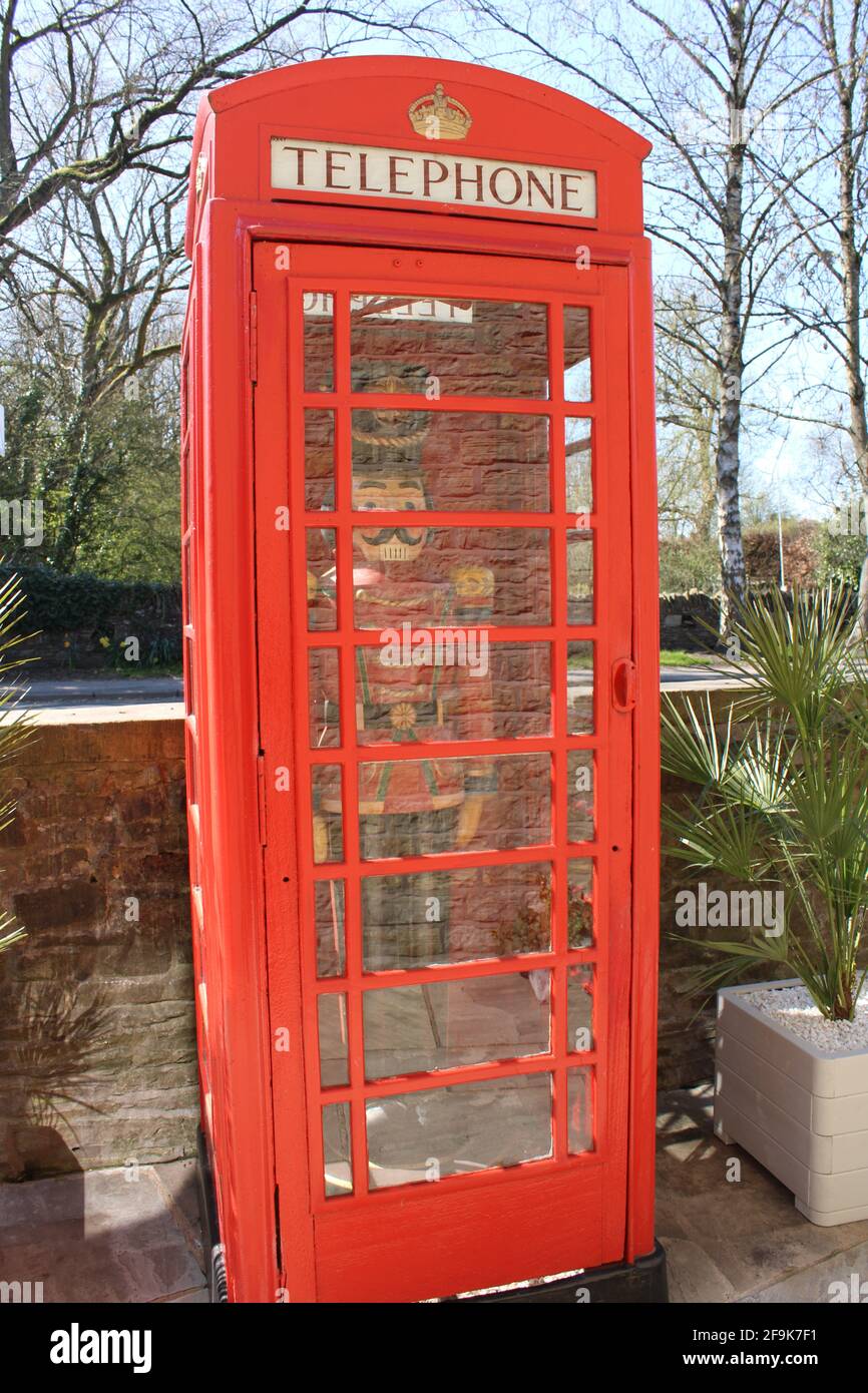 K6 telephone box designed by Giles Gilbert Scott grade 2 listed in Upholland with full size wooden painted soldier in red black and gold uniform in Stock Photo