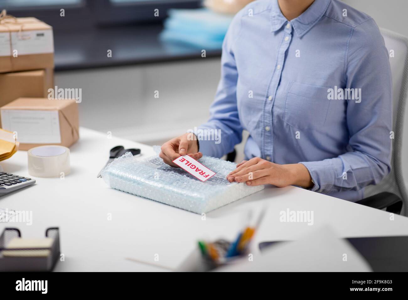 woman sticking fragile mark to wrap at post office Stock Photo