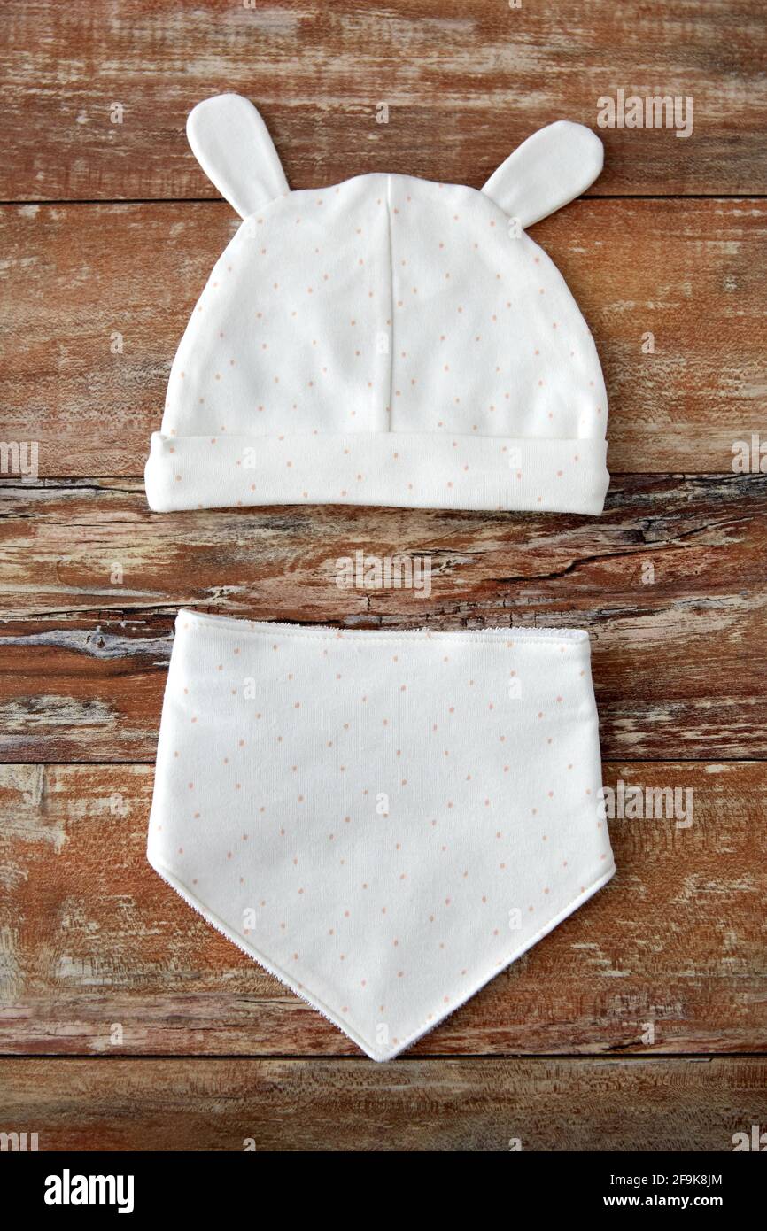 baby hat with ears and bib on wooden table Stock Photo