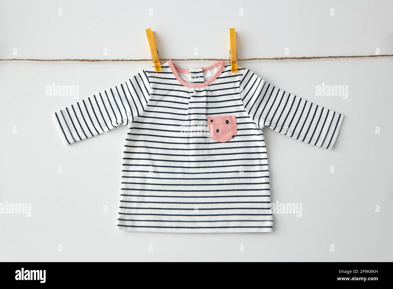 shirt for baby girl hanging on rope with pins Stock Photo