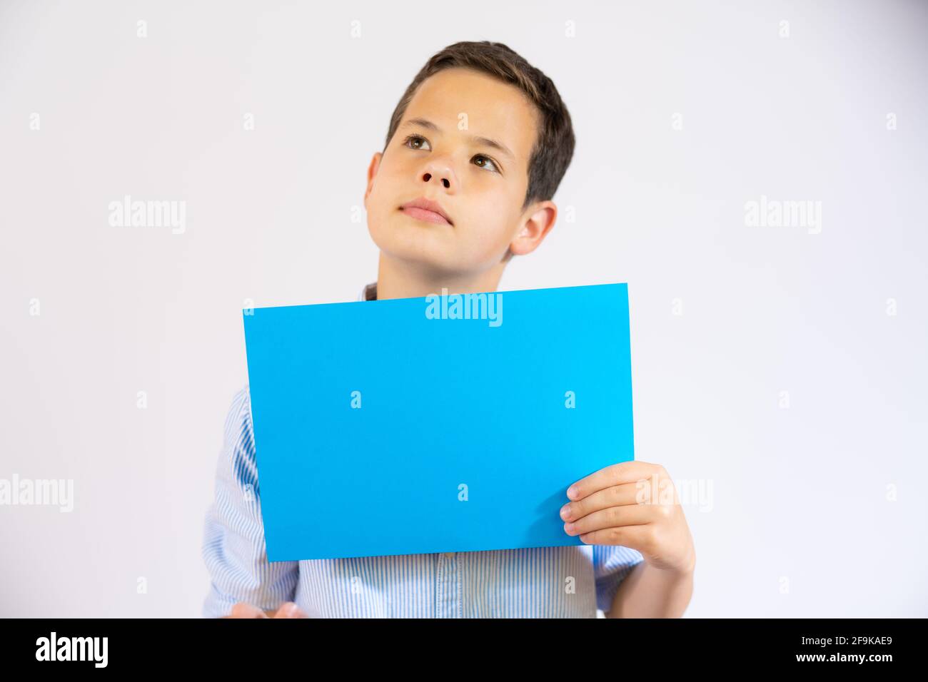 Cute boy holding blue blank paper isolated over white background Stock ...