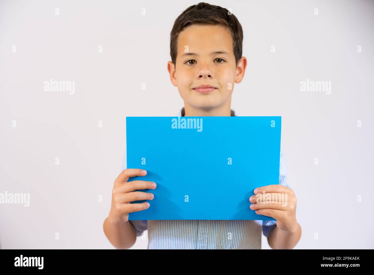Cute boy holding blue blank paper isolated over white background Stock ...