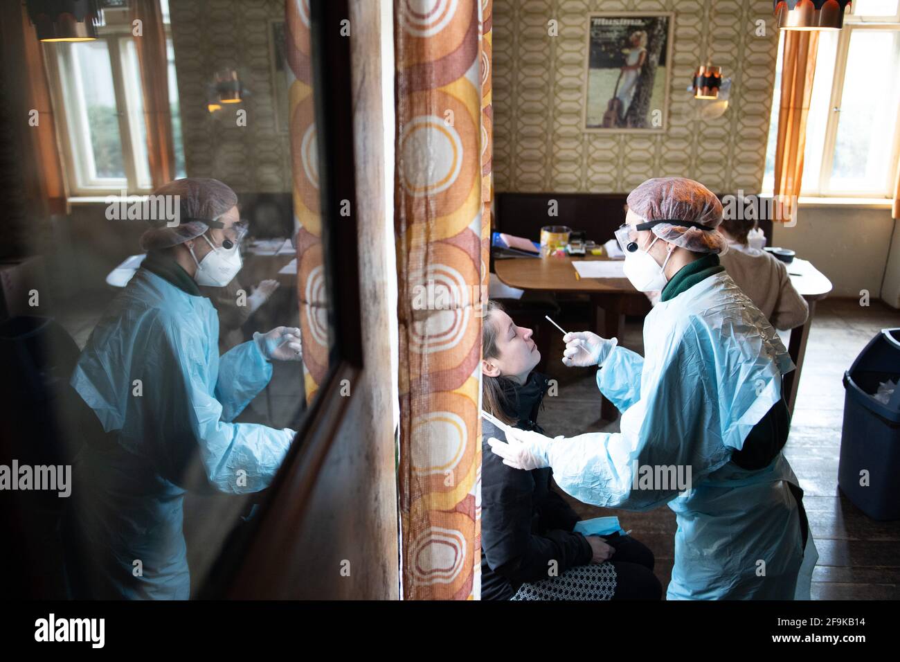 Dresden, Germany. 19th Apr, 2021. Tina Warmuth (l), sits in front of Carlos Dos Reis, freelance dancer, during a Corona quick test at the Ostpol dance and nightclub and reflects in a picture frame. The club offers an antigen quick test in its premises. Credit: Sebastian Kahnert/dpa-Zentralbild/dpa/Alamy Live News Stock Photo