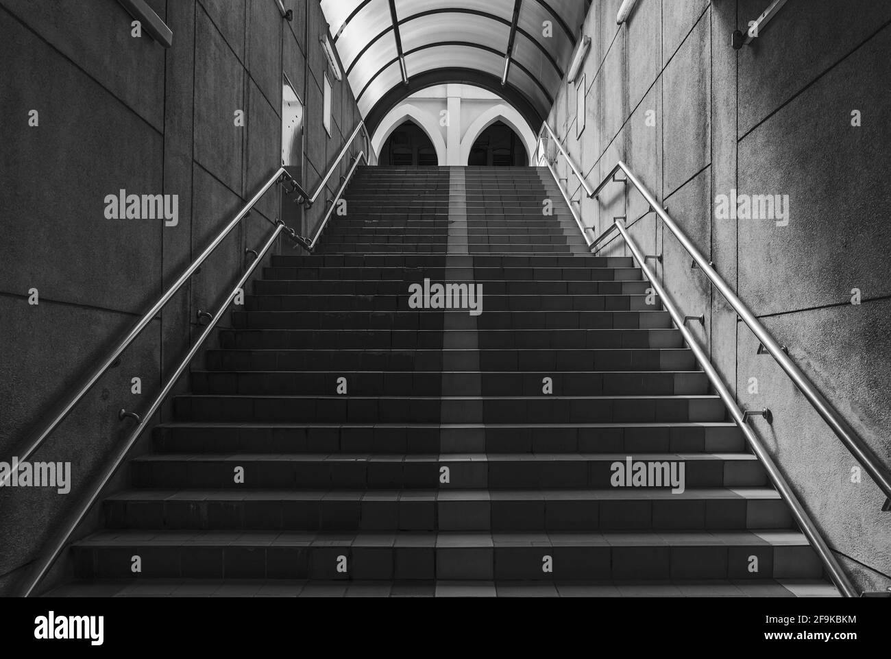 Concrete steps of roofed or covered pedestrian underground underpass tunnel under a road, street or highway, in black and white Stock Photo