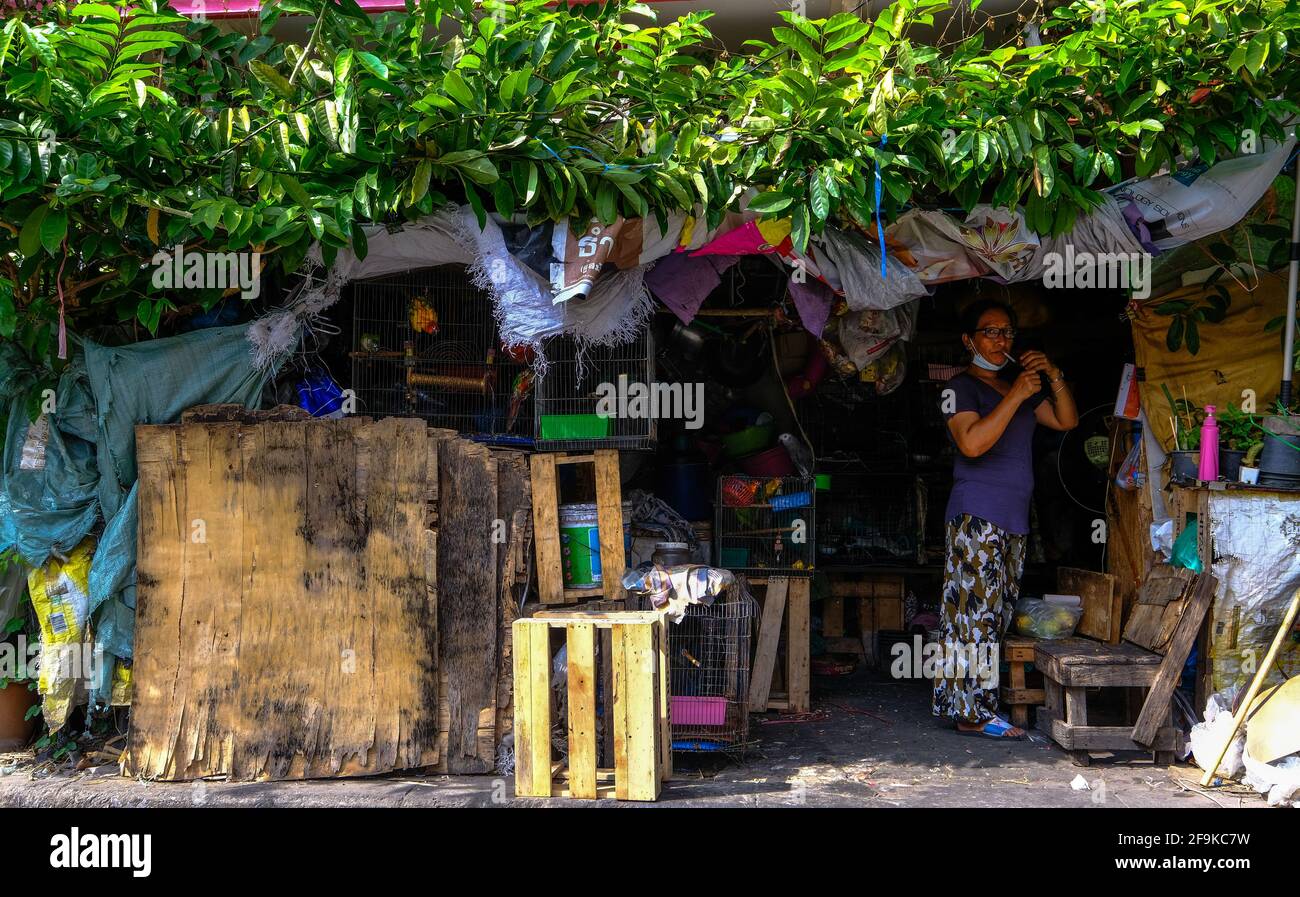 A woman lights a cigarette inside her premises on a small street in