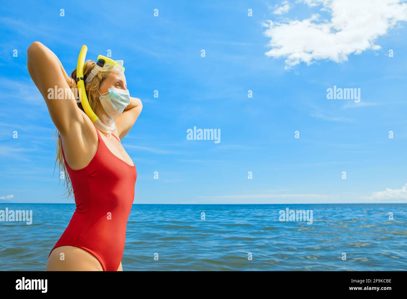 Funny girl in medical and snorkeling masks on sea beach. New rules to wear face covering at public places. New rules to wear cloth face covering mask Stock Photo