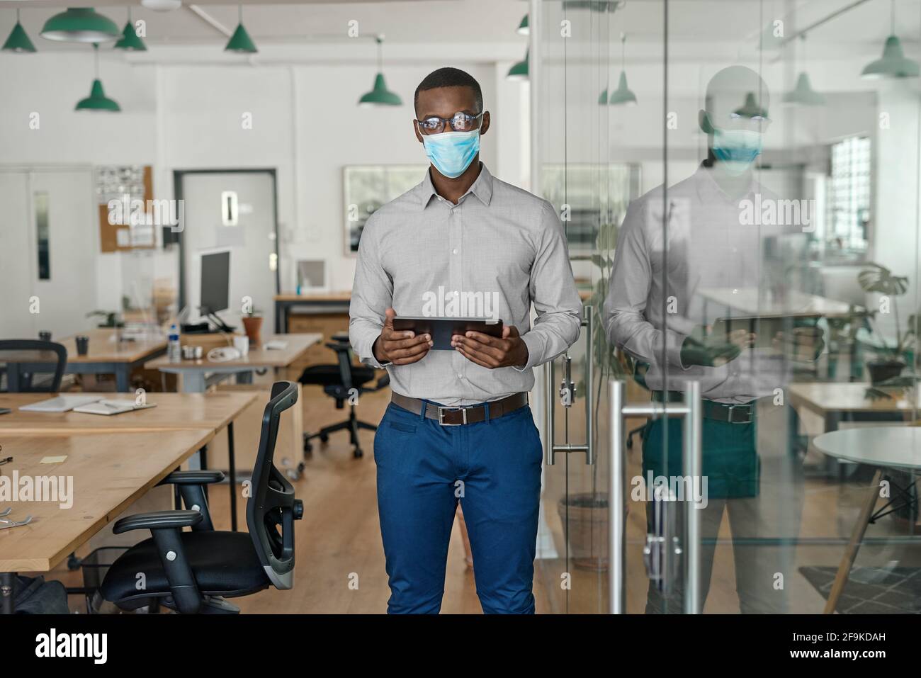 African businessman wearing a face mask working on a tablet Stock Photo