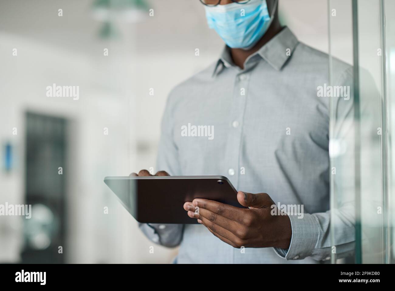 African businessman in a face mask using a digital tablet Stock Photo