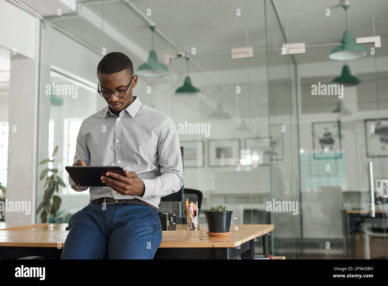 African businessman leaning on an office desk using a tablet Stock Photo