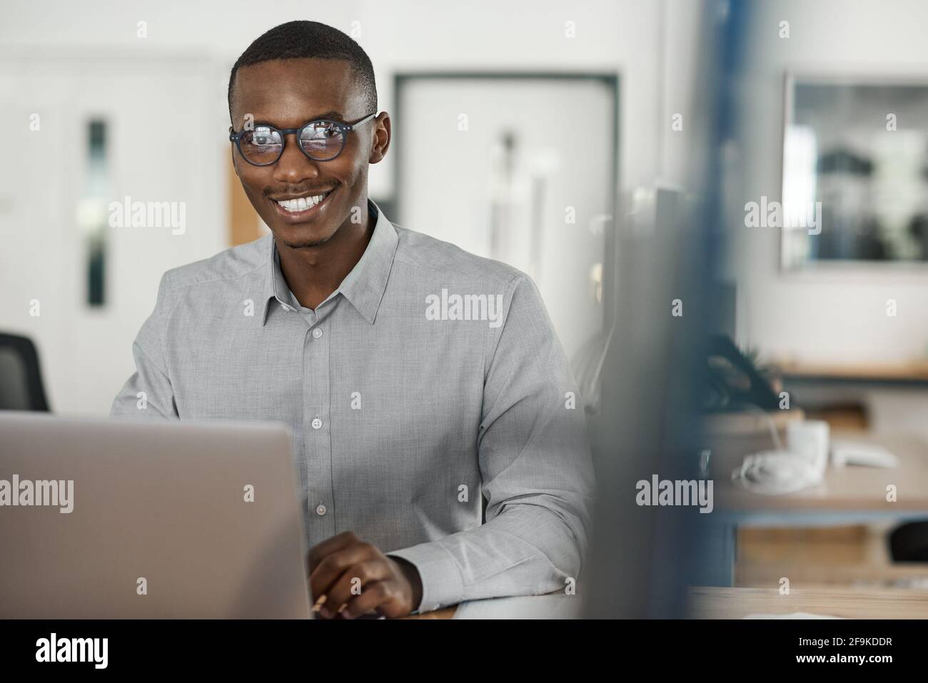 African businessman smiling while using a laptop in an office Stock Photo