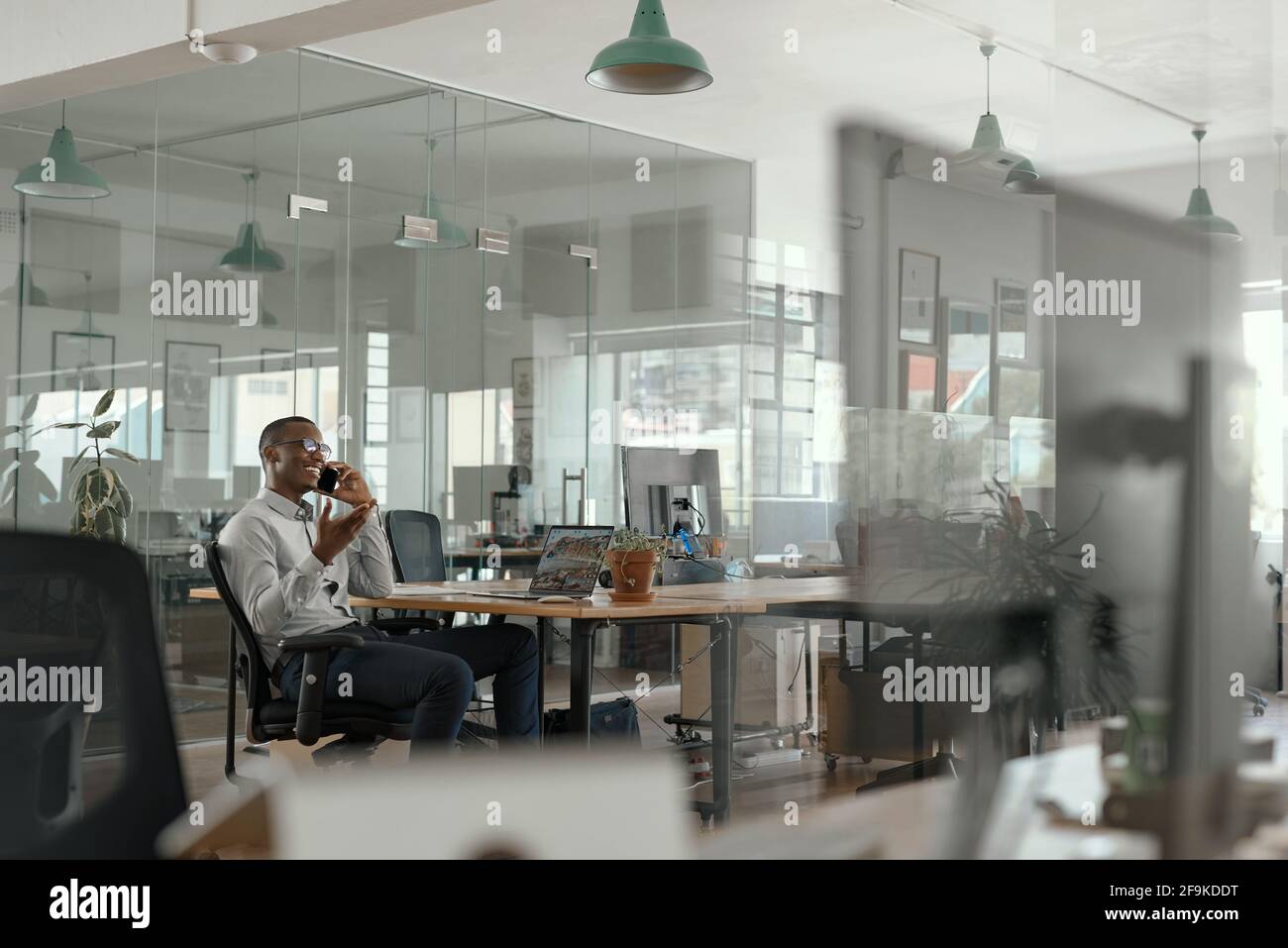 Smiling African businessman talking on his phone in an office Stock Photo