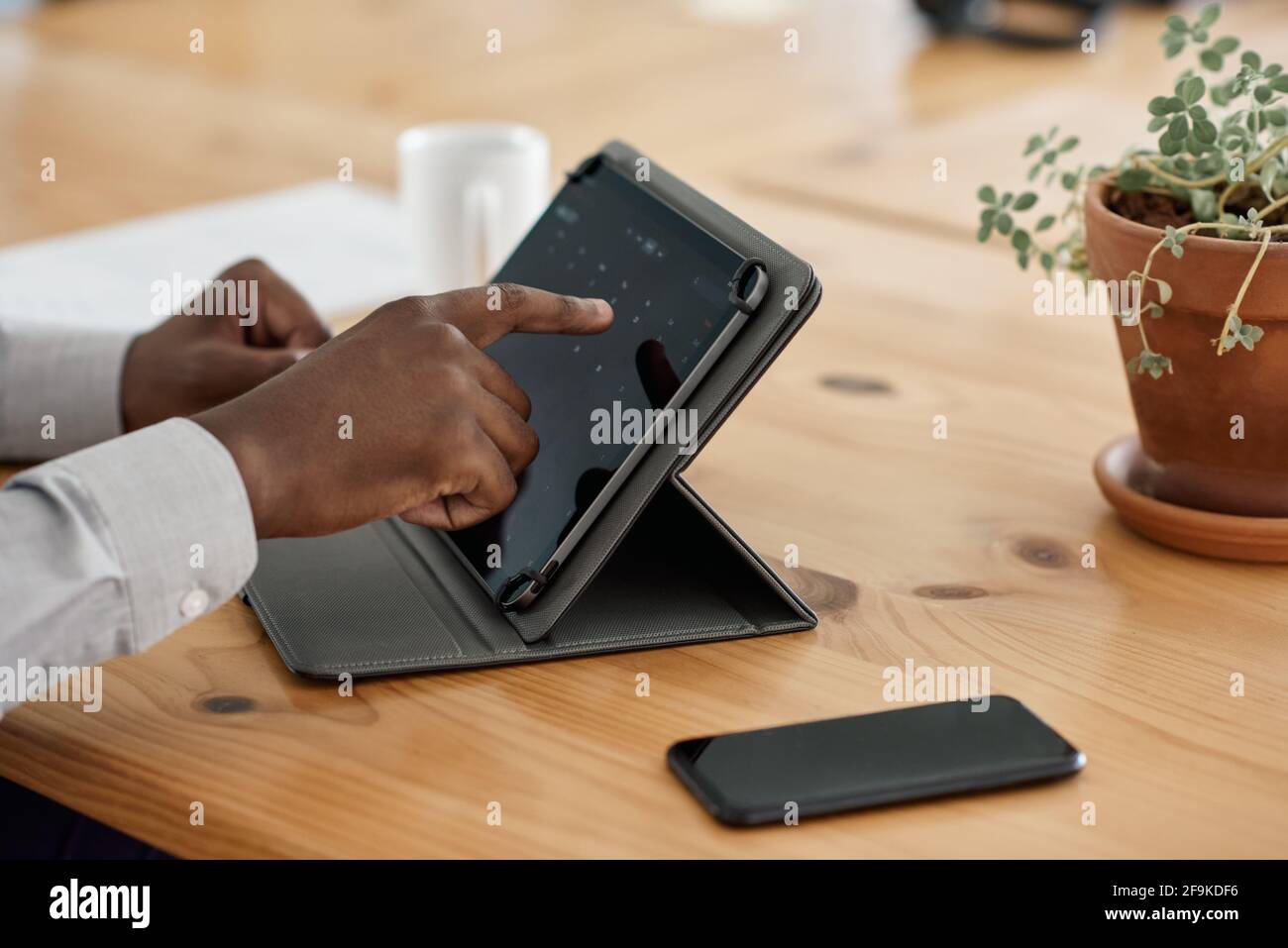 Closeup of an African businessman using a tablet at table Stock Photo