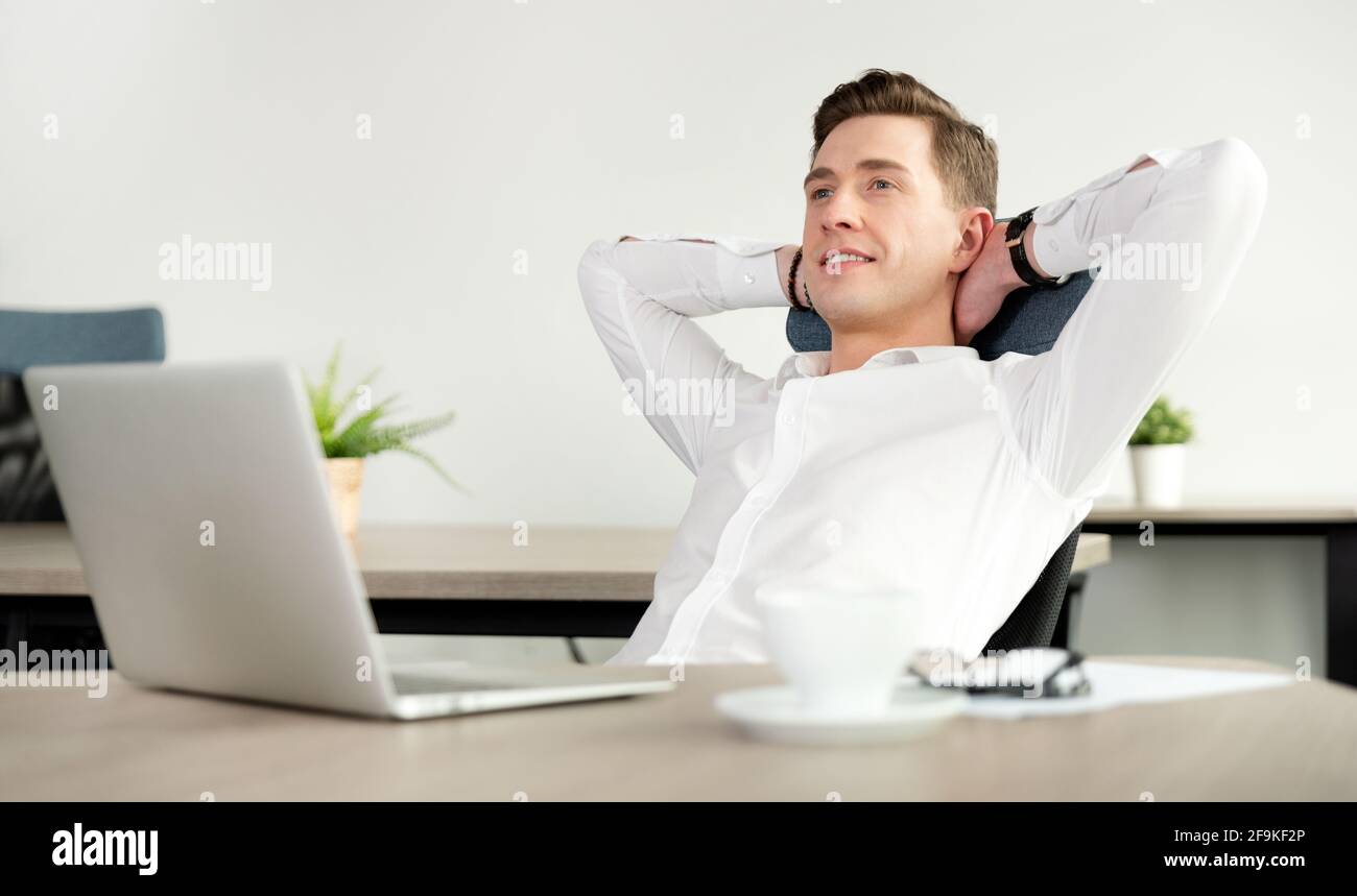 Businessman relaxing in office after hard working day. Happy employee