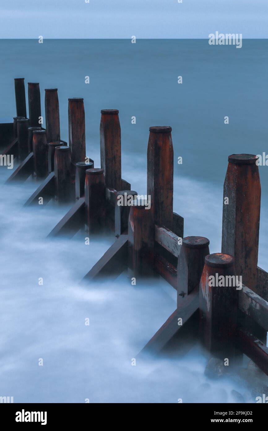 Wooden groyne surrounded by blurred sea waves Stock Photo