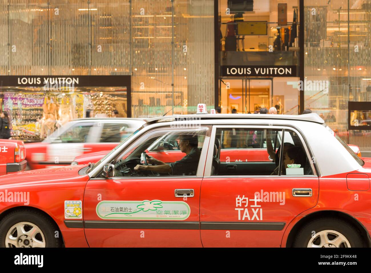 Hong Kong, Central district, China, Asia - Traditional red taxis in front of a Louis Vuitton store at Central district Hong Kong. Stock Photo