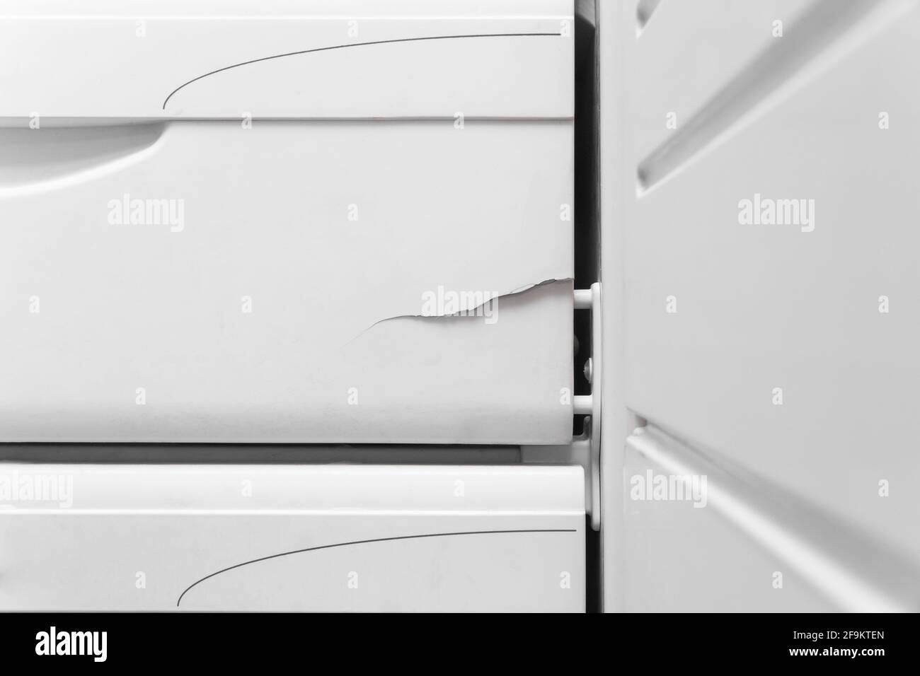 Crack on the polystyrene lid of the refrigerator freezer, close-up. The need to repair the refrigerator. Stock Photo