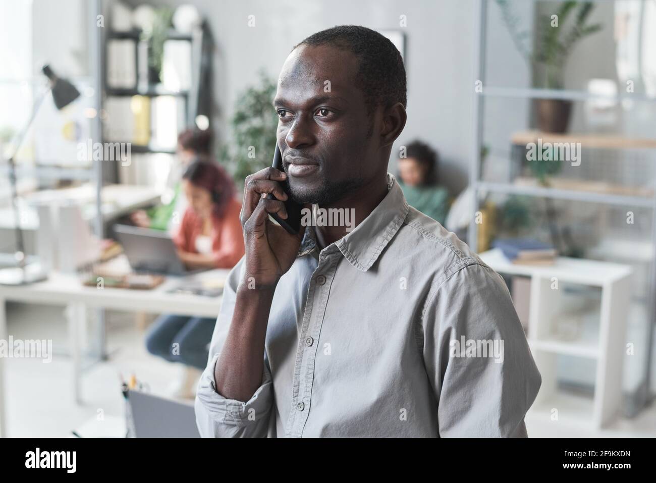 African young businessman talking on mobile phone while working at office Stock Photo