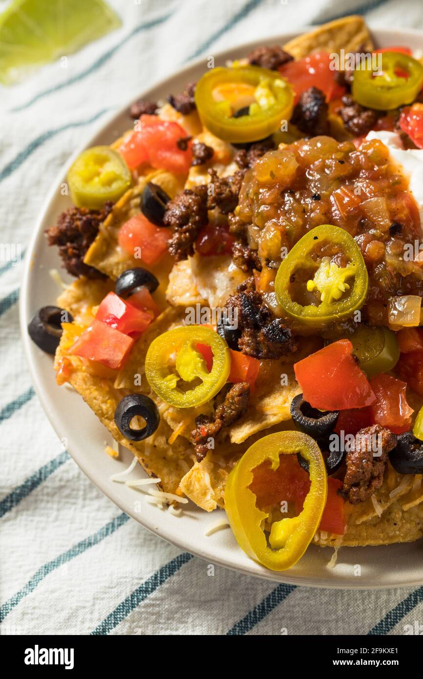 Homemade Cheesy Beef Nachos with Olives and Jalapenos Stock Photo