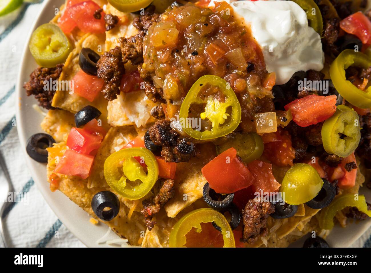 Homemade Cheesy Beef Nachos with Olives and Jalapenos Stock Photo