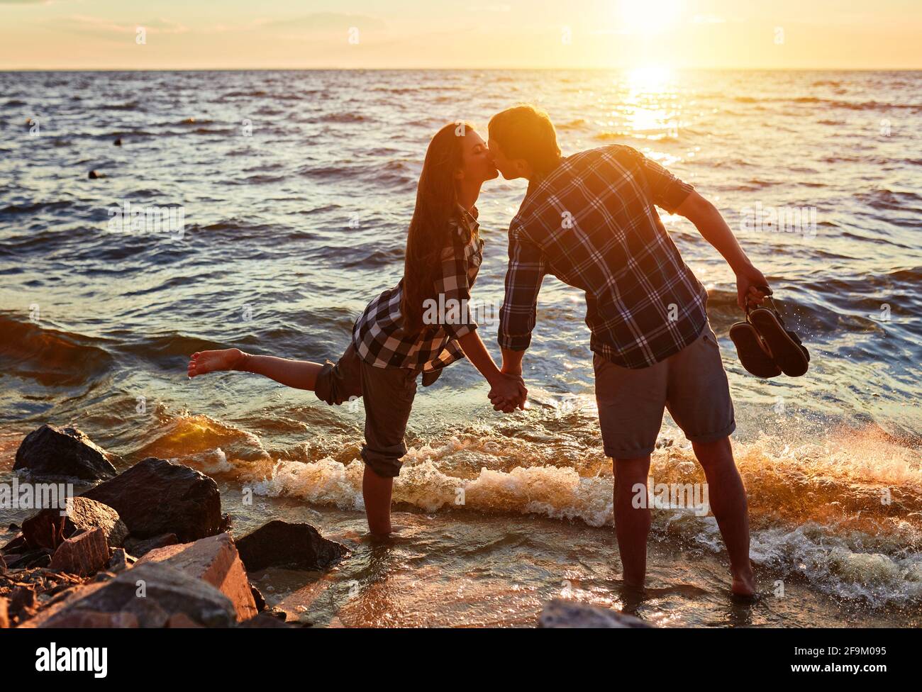 Couple walking on the beach at sunset Stock Photo - Alamy