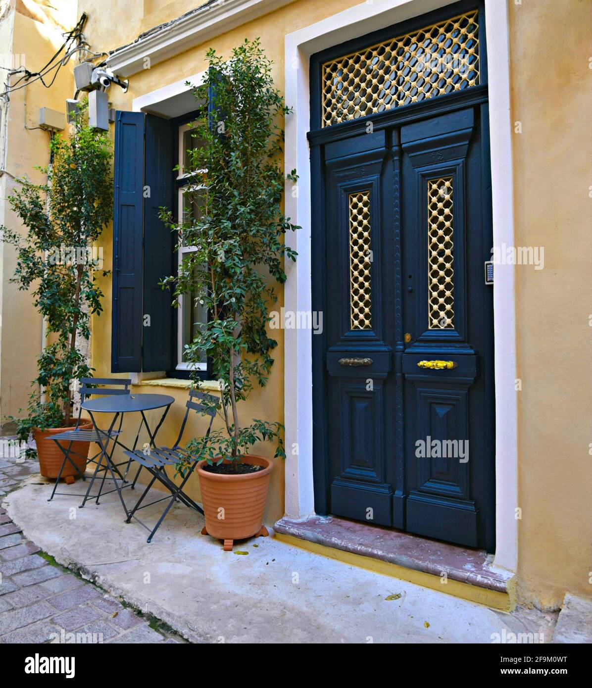 Neoclassical house facade with an ochre stucco wall and a blue entrance door at the Old Town district of Chania in Crete island, Greece. Stock Photo