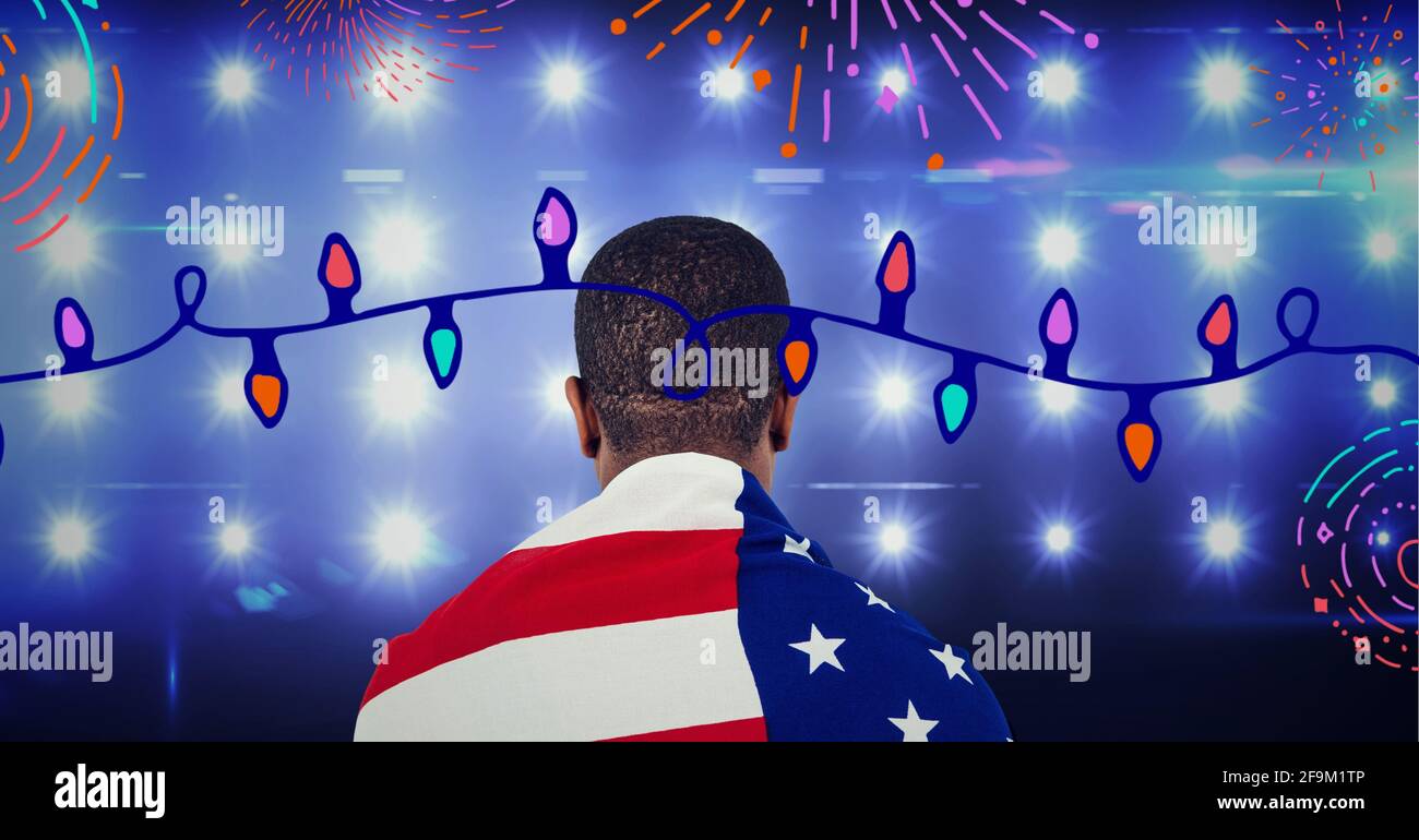 Composition of fireworks and fairy lights with man wrapped in american flag over stadium spotlights Stock Photo