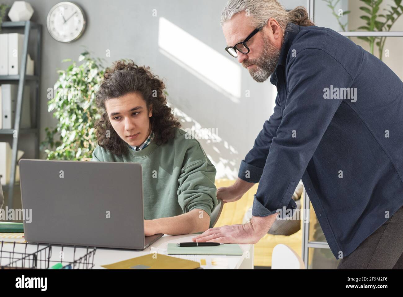 Mature teacher talking to his student and explaining the material on laptop during lesson Stock Photo