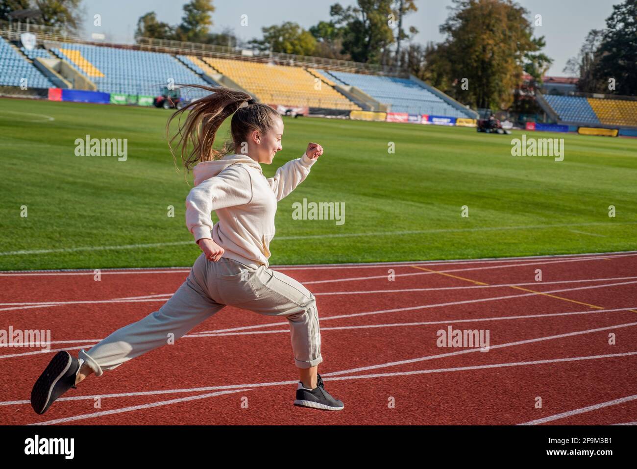 The rule in running is just run. Energetic girl run on running track. Sports school Stock Photo