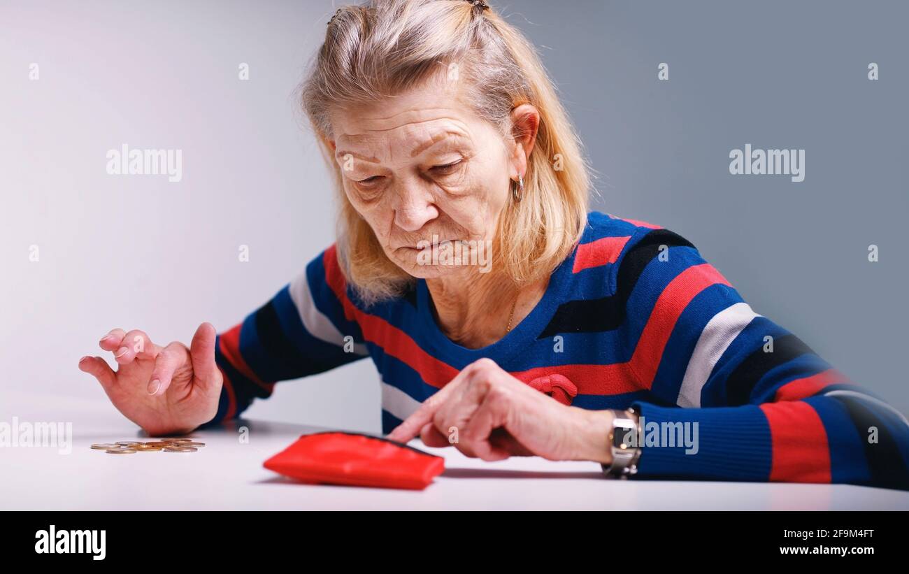 sad poor elderly woman counting coins and looking at an empty wallet. High quality photo Stock Photo