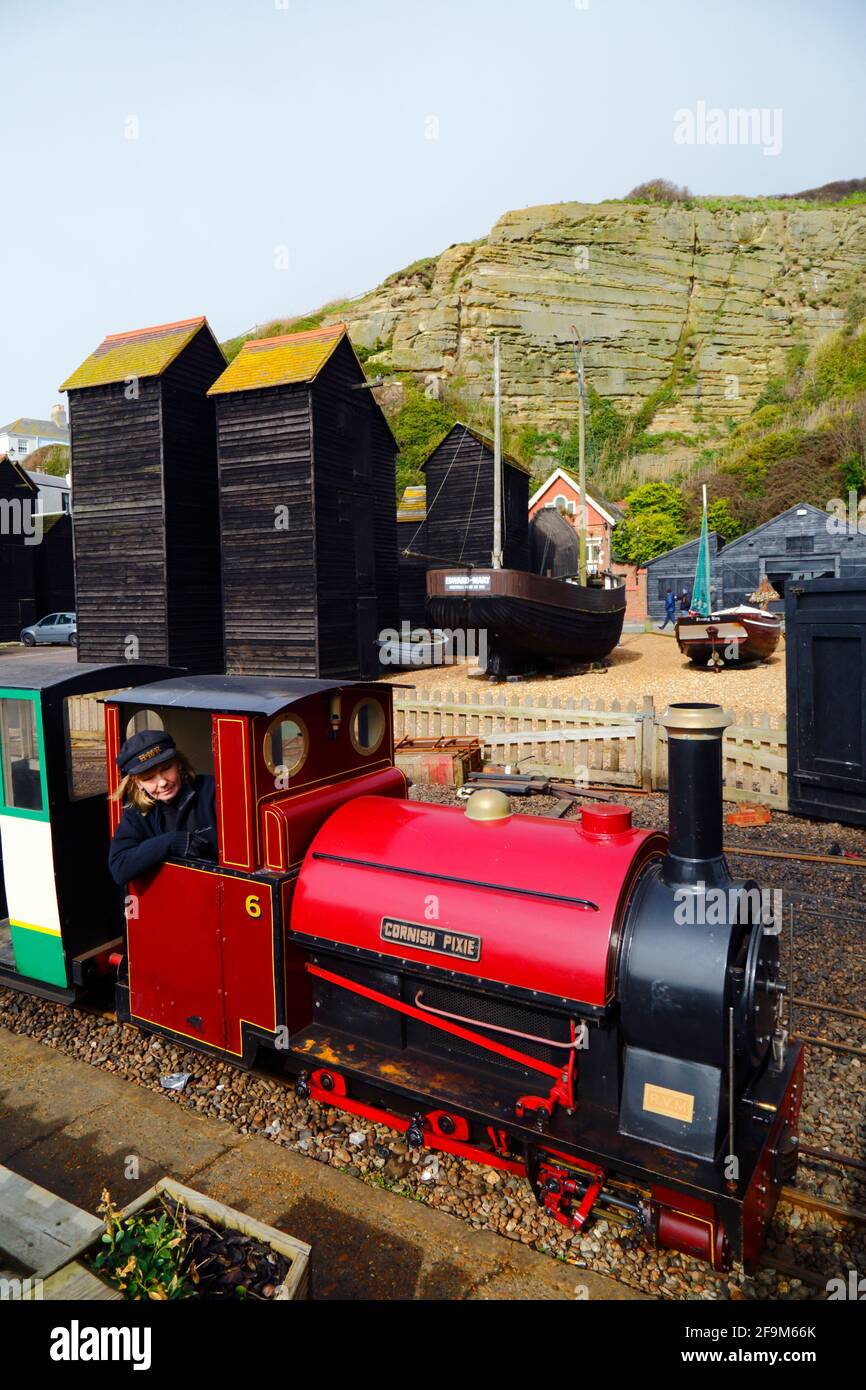 Woman driving 'Cornish Pixie' steam engine past historic wooden Net Shops on Hastings Miniature Railway, Hastings, East Sussex, England Stock Photo