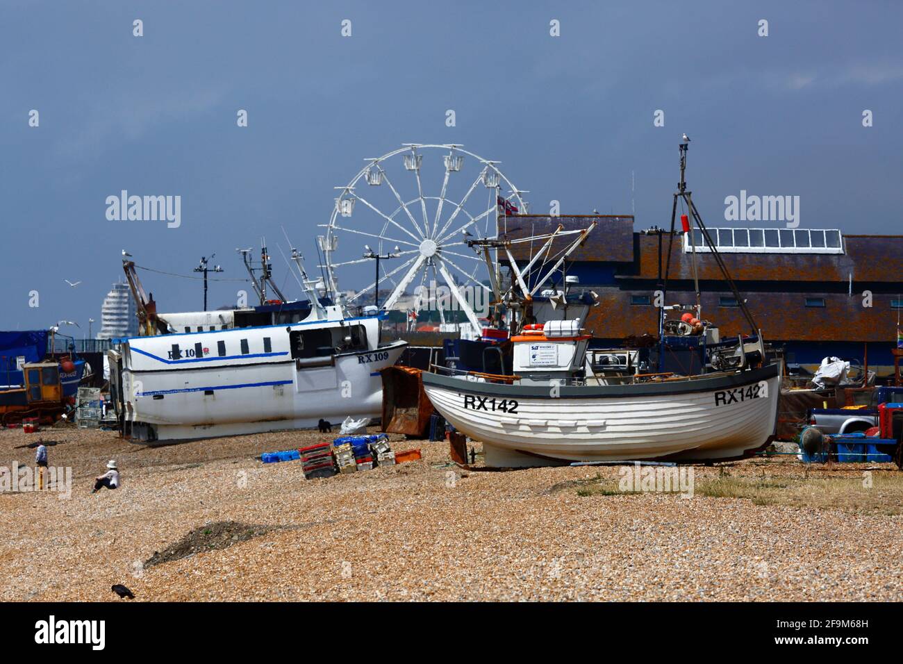 Fishing boats on The Stade shingle beach, Hastings Ferris Wheel in background, Hastings, East Sussex, England, UK Stock Photo