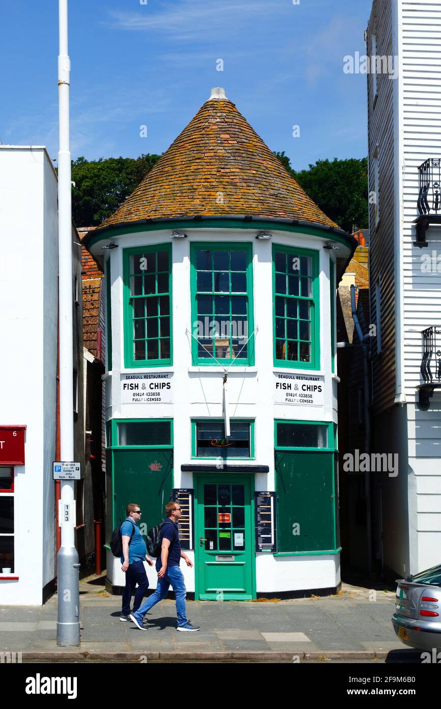 Young men walking past The Seagull fish and chips restaurant on sea front, Hastings, East Sussex, England Stock Photo