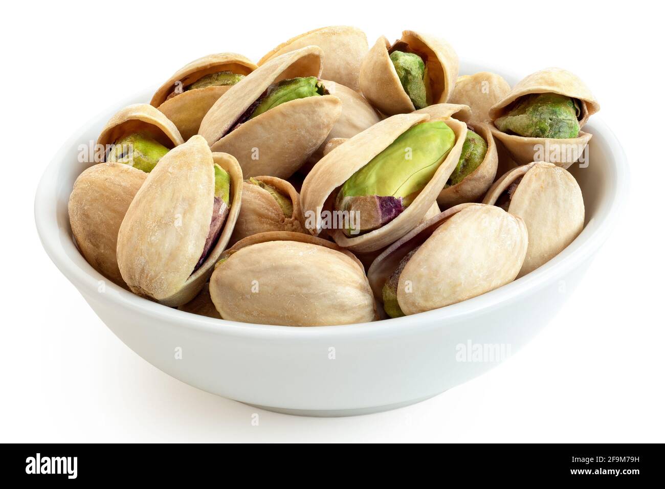 Salted pistachios in shell in a white ceramic bowl isolated on white. Stock Photo