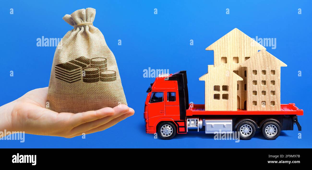 Money bag, red freight truck loaded with figure houses. Relocation of buildings and monuments. Cargo transportation, delivery service. A moving compan Stock Photo
